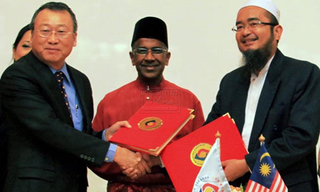 INKED: Daud (centre) witnessing the exchange of MoU between Peter (left) and Nasiruddin.
